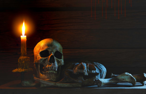 Still life style ;Skulls of bones with candle flame, Pumpkin at night on back background.Halloween day concept.