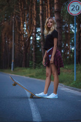Naklejka premium A beautiful girl in a black T-shirt and white shorts skates on a skateboard. Street style. Summer
