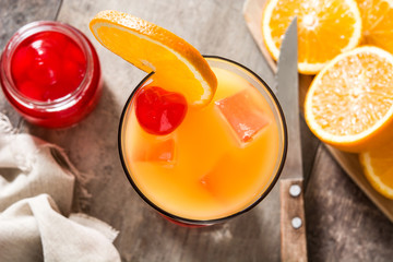 Tequila sunrise cocktail in glass on wooden table. Top view