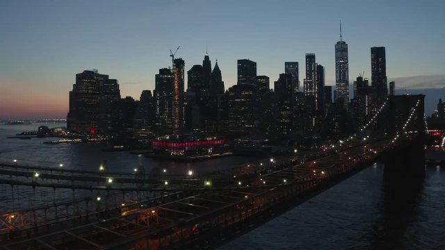 night view of downtown Manhattan flying bkwd alongside Bkln Bridge