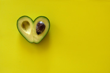 Heart-shaped avocado on yellow background