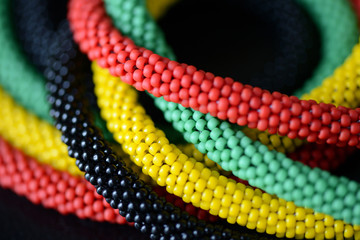 Fragment of a beaded necklace in Jamaican style on a dark background close up