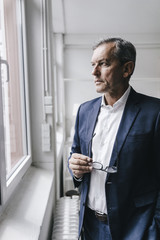 Serious mature businessman looking out of window