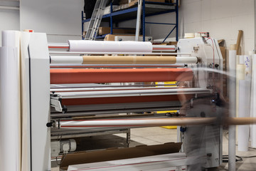 Big printing laminator armed with glossy paper rolls and transparent film.