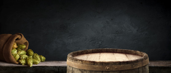 Oktoberfest beer barrel and beer glasses with wheat and hops on wooden table
