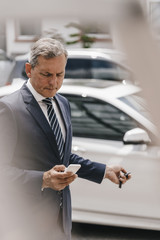 Businessman checking message while using remote control key of car
