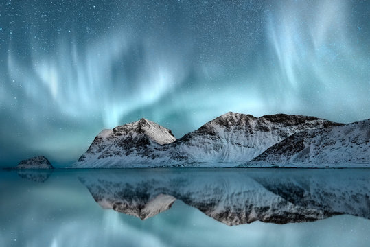 Aurore bor&eacute;ale sur la plage d'haukland avec sa montagne en reflet