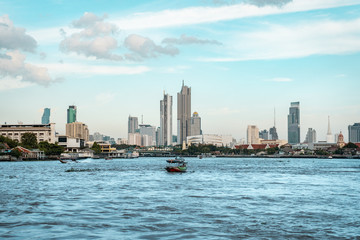 Naklejka premium View of Bangkok skyline with the skyscrapers in background and Chao Phraya River in the foreground during bright sunny day, Bangkok, Thailand