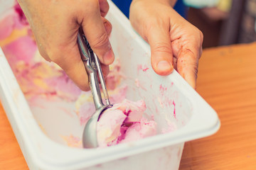 The hand puts an ice cream ball from the container.