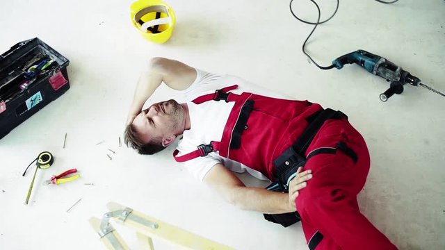 Top view of an injured man lying on the floor after an accident at work.