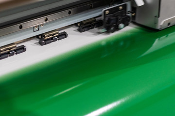 Big professional oversized printer, outputting a deep green glossy color sample sheet for best quality and performance.