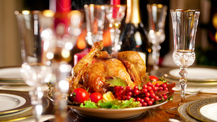 Closeup image of glasses, champagne and baked hot chicken on festive dinner