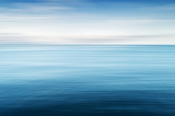 Abstract background of blue sea and cloudy sky over it. Motion blur sea water and sky with white clouds.