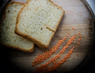 Homemade bread on a wooden plate with grains of lentils.