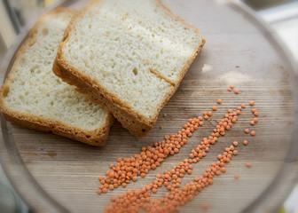 Homemade bread on a wooden plate with grains of lentils.