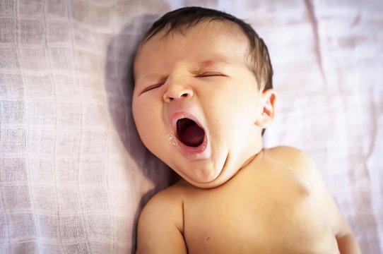Funny newborn baby girl yawning with a trace of mother milk on her lips. Breast feeding baby concept, breastfeeding. Sleepy infant fall asleep.