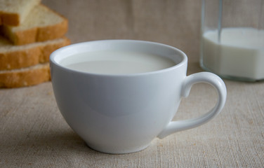 A cup of milk and pieces of white bread.