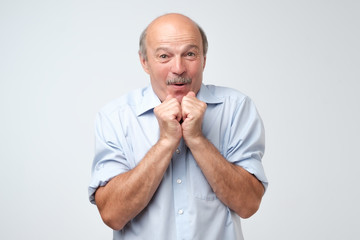 Portrait of joyful handsome mature man clapd palms, waits to hear something pleasant, recieves...