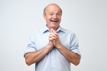 Portrait of joyful handsome mature man clapd palms, waits to hear something pleasant, recieves...