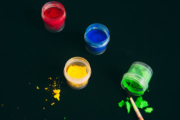 Gouache on black background. Blue, yellow and green red gouache. A set of gouache