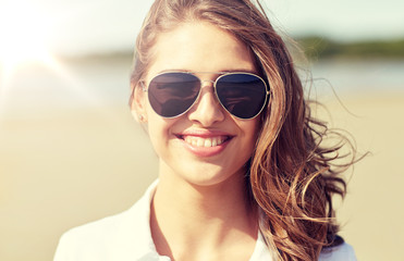 Naklejka premium summer vacation, holidays, eyewear and people concept - smiling young woman in sunglasses on beach