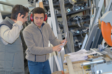 workers in protective uniforms by steel sheet metal profiles