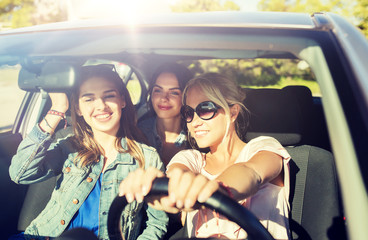 summer vacation, holidays, travel, road trip and people concept - happy teenage girls or young women driving in car