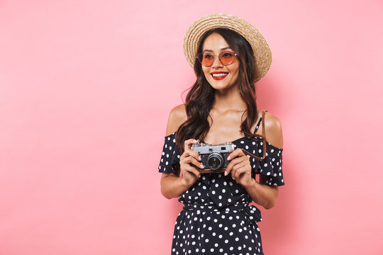 Smiling brunette woman in straw hat and sunglasses posing