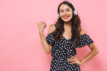 Smiling brunette woman in dress and headphones listening music