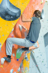 Fototapeta na wymiar Young man climbing indoor wall