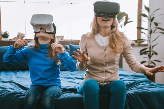 New innovations. Cute nice mother and daughter being in the virtual reality while using modern technologies - Powered by Adobe