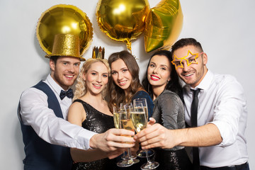 celebration, luxury and holidays concept - happy friends with golden party props clinking champagne glasses