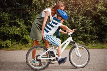Sister and little brother learning to ride bicycle park having fun together