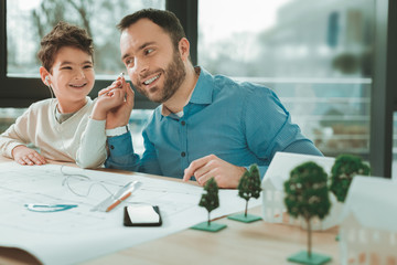 Wonderful music. Nice joyful man taking a headphone while sitting together with his son