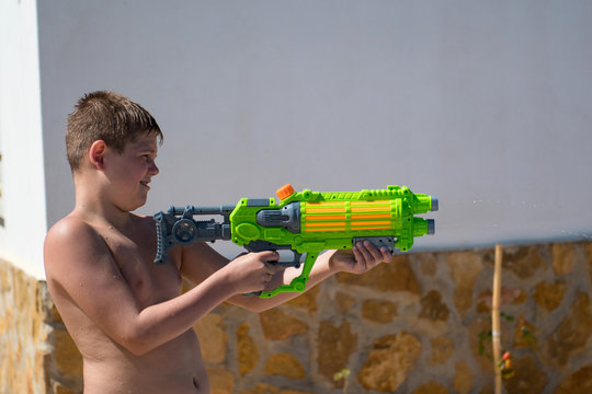 The boy play with water gun in the garden.