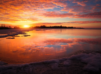 Beautiful colorful winter landscape with frozen lake and sunset sky. Unusual weather phenomenon