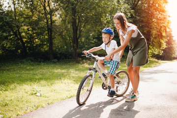 Sister and little brother learning to ride bicycle park having fun together