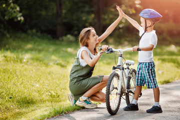 Sister gives five hands to her younger brother for success. Concept of riding bike