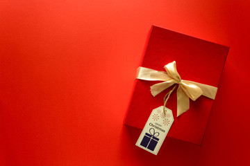 Top view on Christmas gifts wrapped in gift paper decorated with ribbon on red paper background. New Year, holidays and celebration decorations concept. Copy space. Flat lay