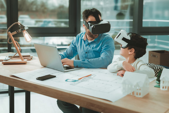 My work. Delighted joyful man sitting in front of the laptop while wearing virtual reality glasses