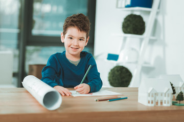 Young talent. Positive talented boy holding pencils while doing a drawing