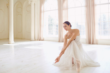 Fototapeta premium A ballerina in white clothes in a white light studio.