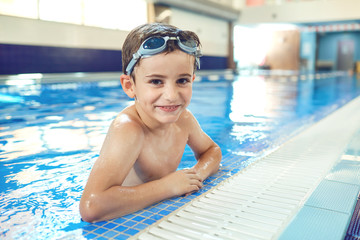 Little boy smiling child smiling at swimming pool indoors.