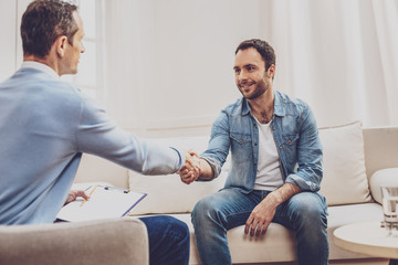 Nice to meet you. Positive delighted man looking at his psychologist while greeting him