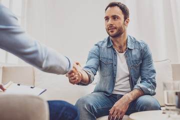 Good morning. Pleasant handsome man shaking hands with his psychologist while greeting him