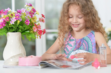 Portrait of little girl reading magazine at home