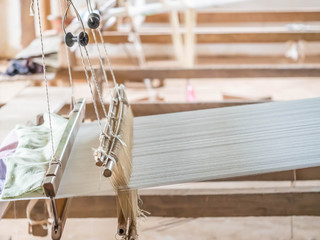 Closeup of wooden loom with white cotton thread for weaving.