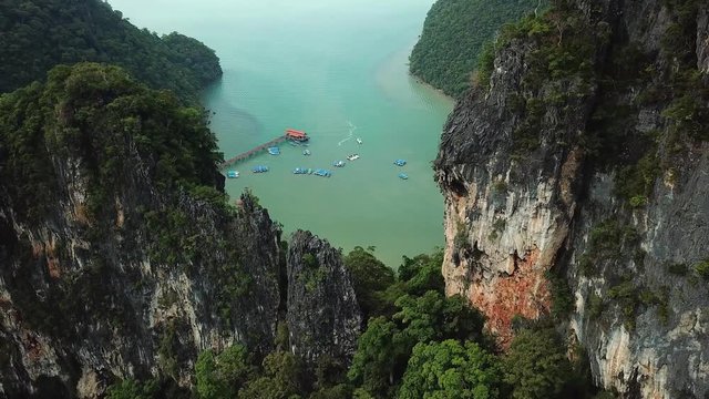 Aerial side drift Scenic pattern surface mountain rocks cliff. Dayang Bunting Island Wild untouched tropical nature landscape. Quay pier boats Sea blue water Rain forest Exotic Malaysia Langkawi Asia.