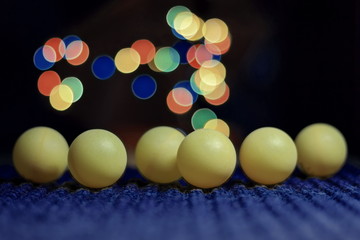 Yellow ping pong ball, with bokeh background, on black background