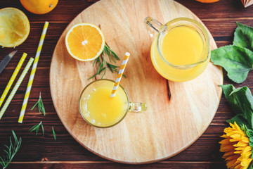 Glass of fresh pressed orange juice and oranges on wooden table. Autumn cozy rustic mood still life